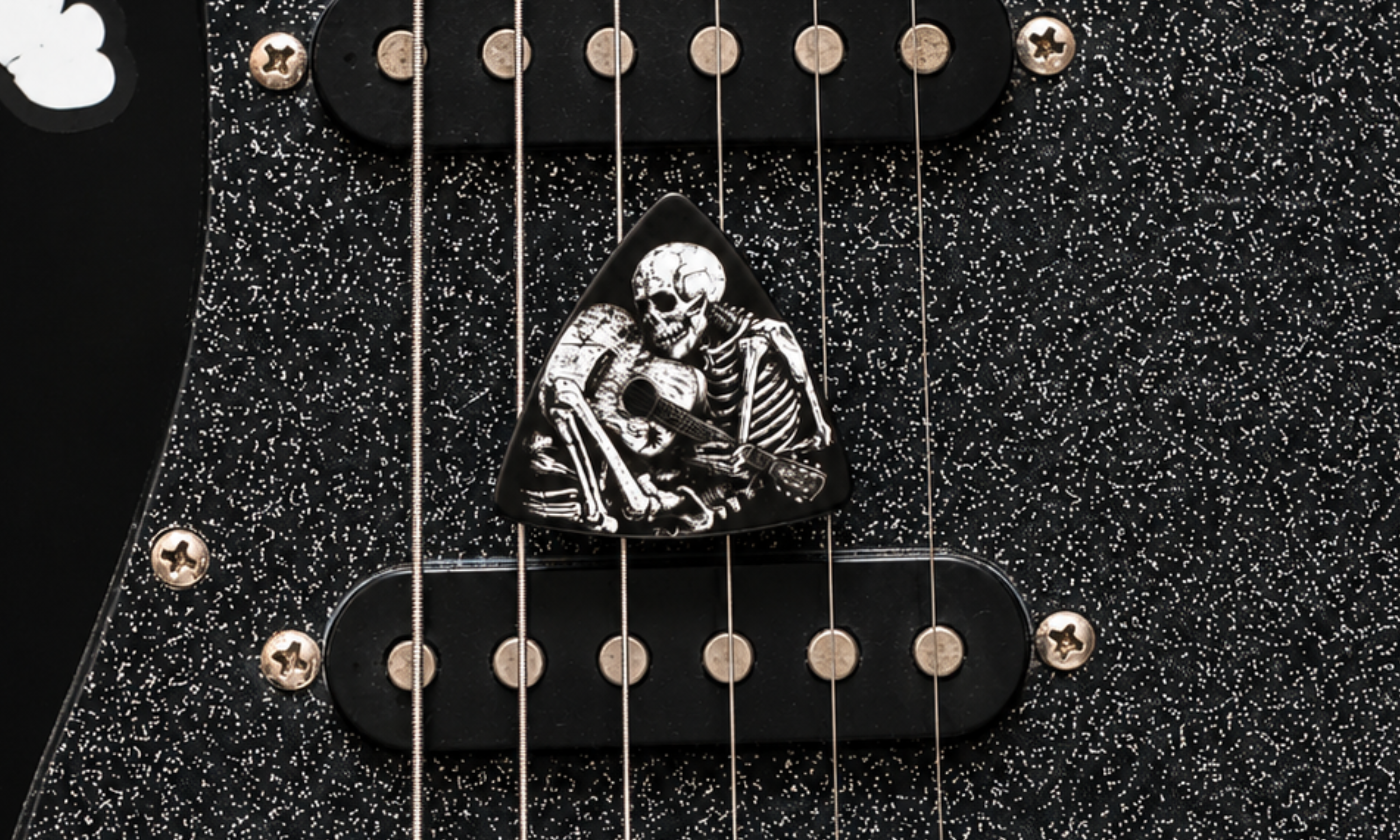 DORTI 'Til Death skeleton guitar pick on a black sparkle electric guitar