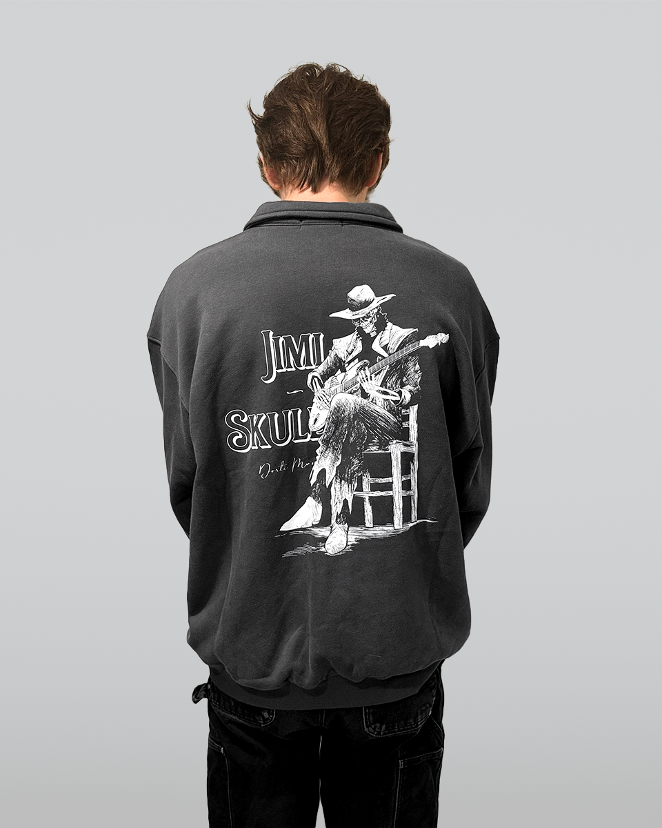 Person wearing a black DORTI jacket with a Jimi Skull graphic design on the back, featuring a stylized illustration of a Jimi Skull playing guitar..