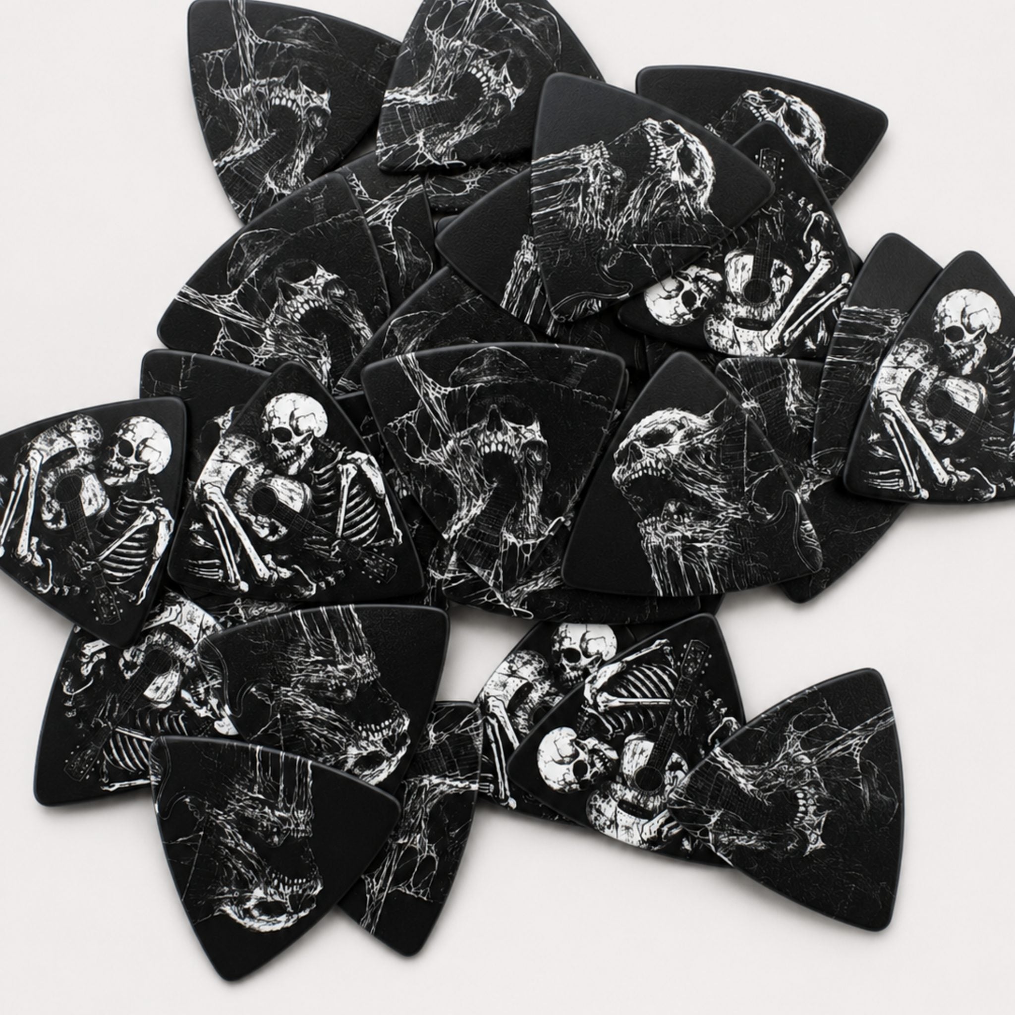 A pile of DORTI Boneyard Collection triangle guitar picks with white skeleton artwork